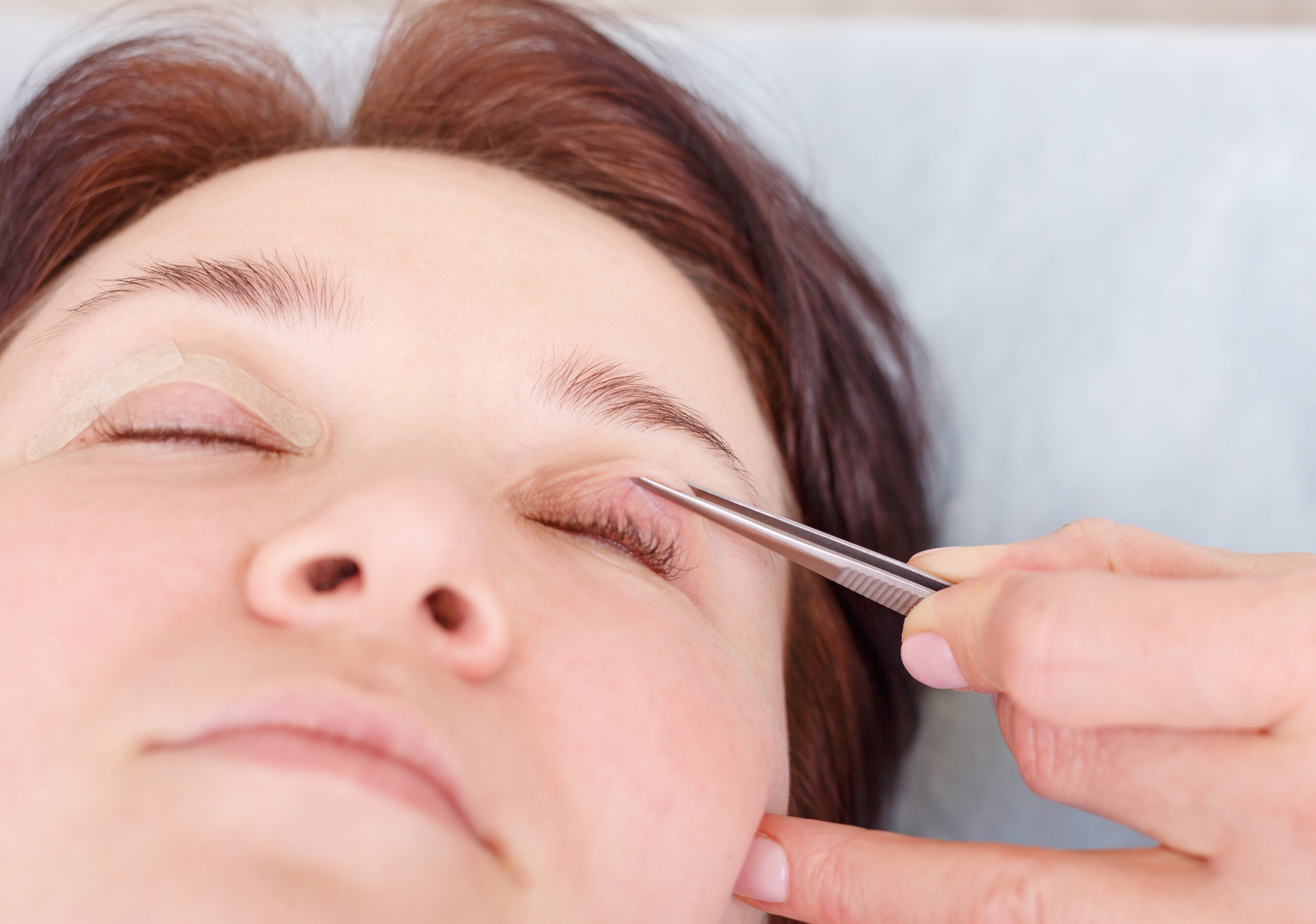 Female surgeon applies a bandage to the female patient's eyelids after a blepharoplasty operation. Close up portrait